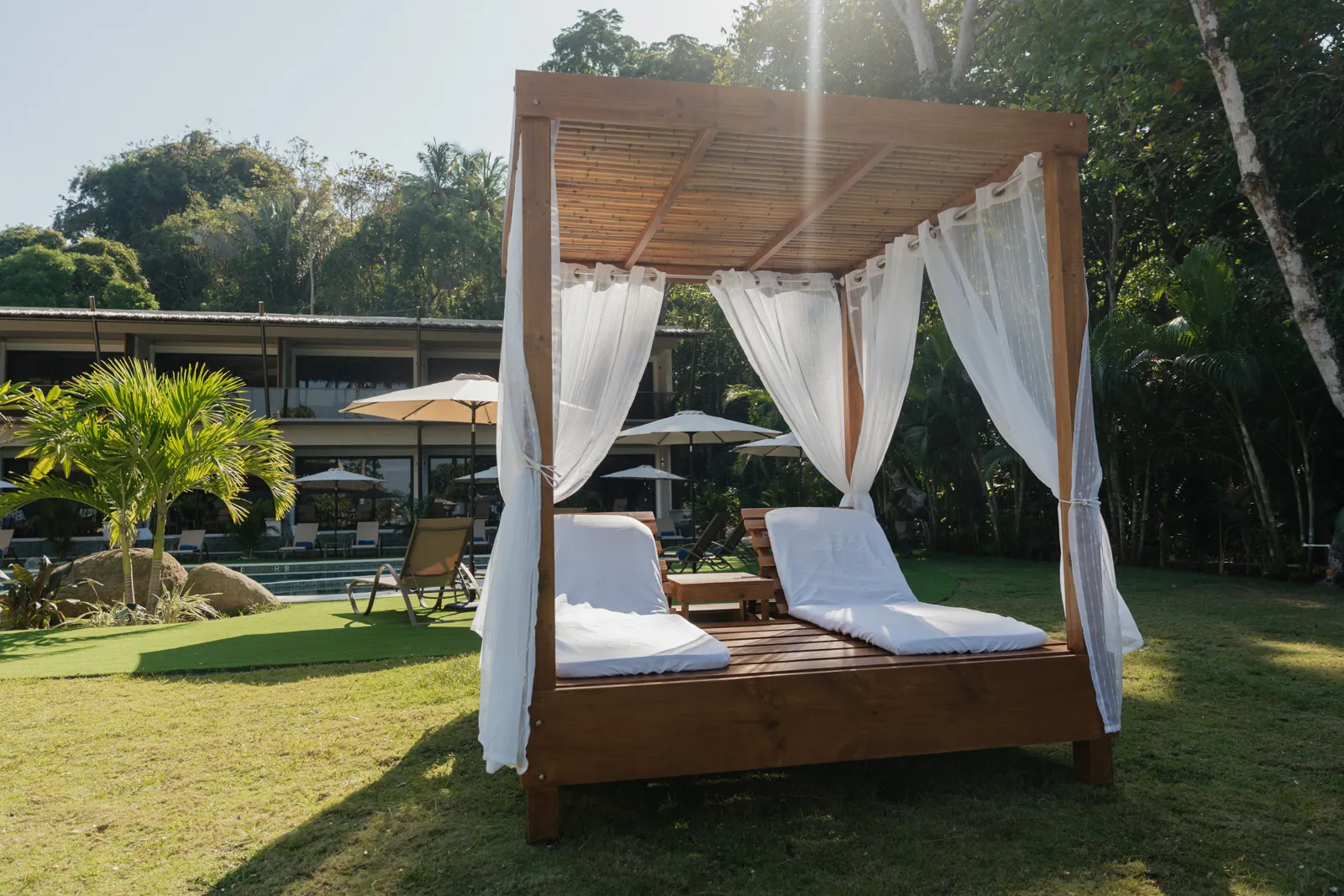 A curtained daybed on the lawn by the pool