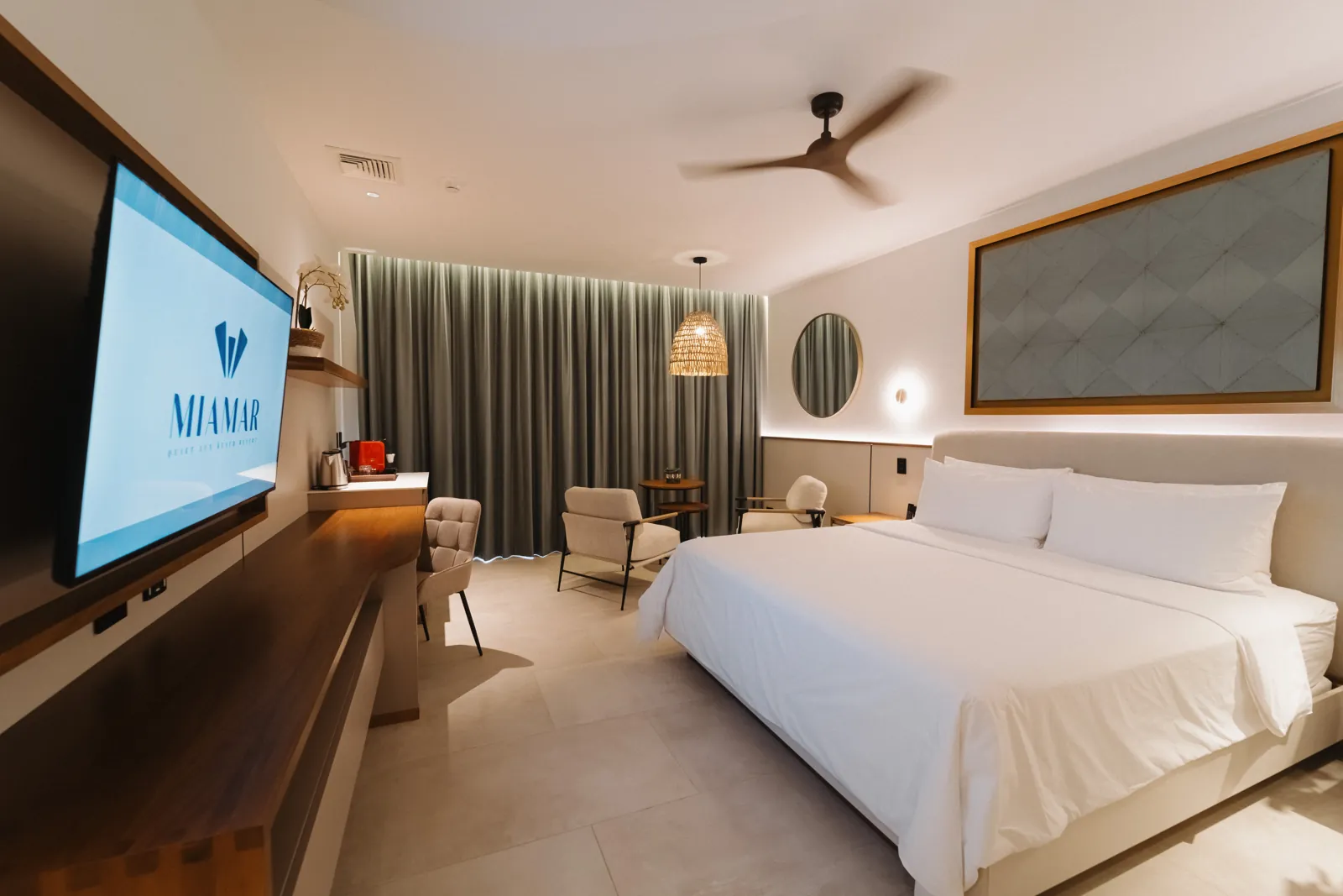 A Miamar suite: king bed in white linens, sitting area and ceiling fan