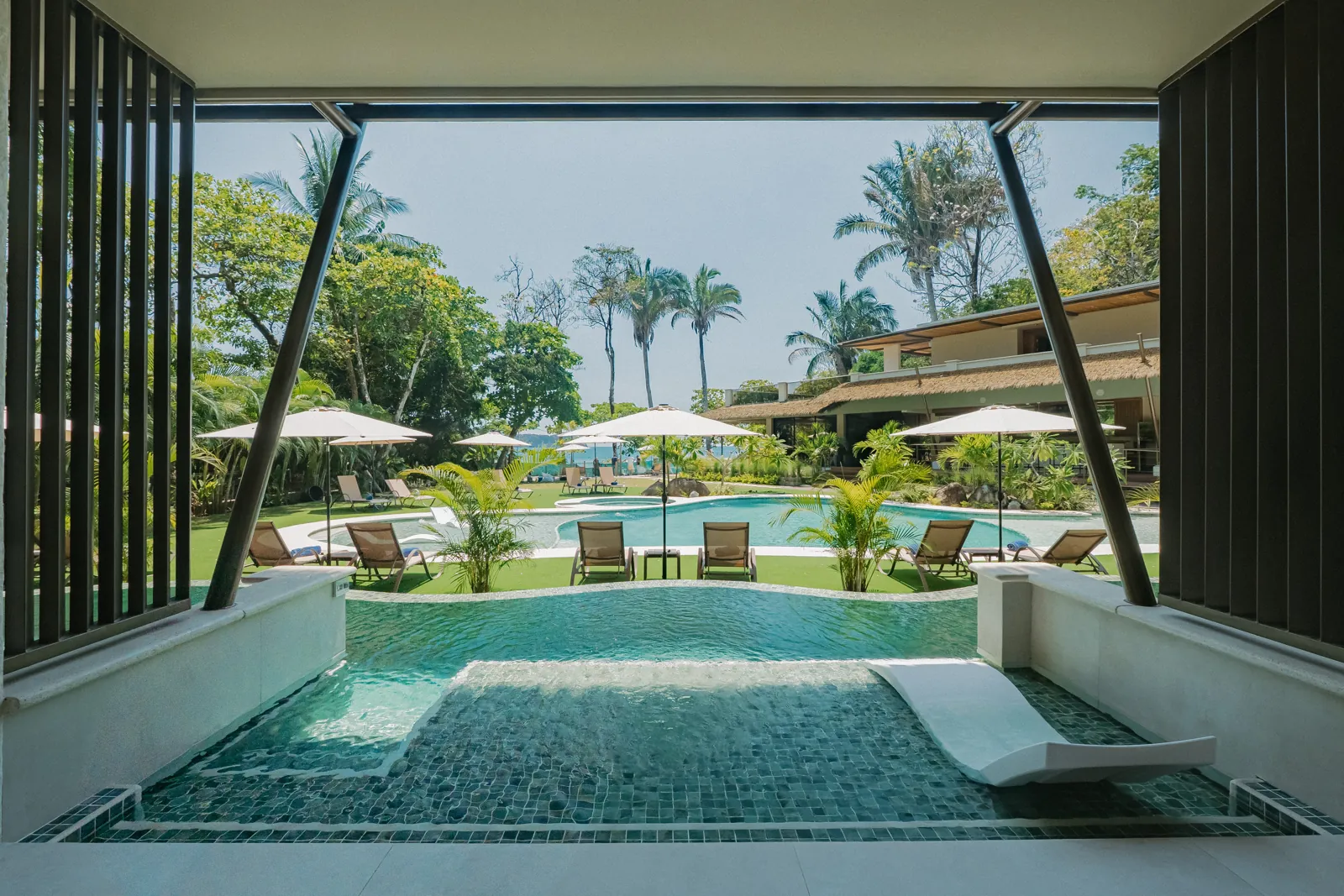 From a Water Channel Suite terrace: the curved plunge pool, the gardens and the ocean beyond the palms