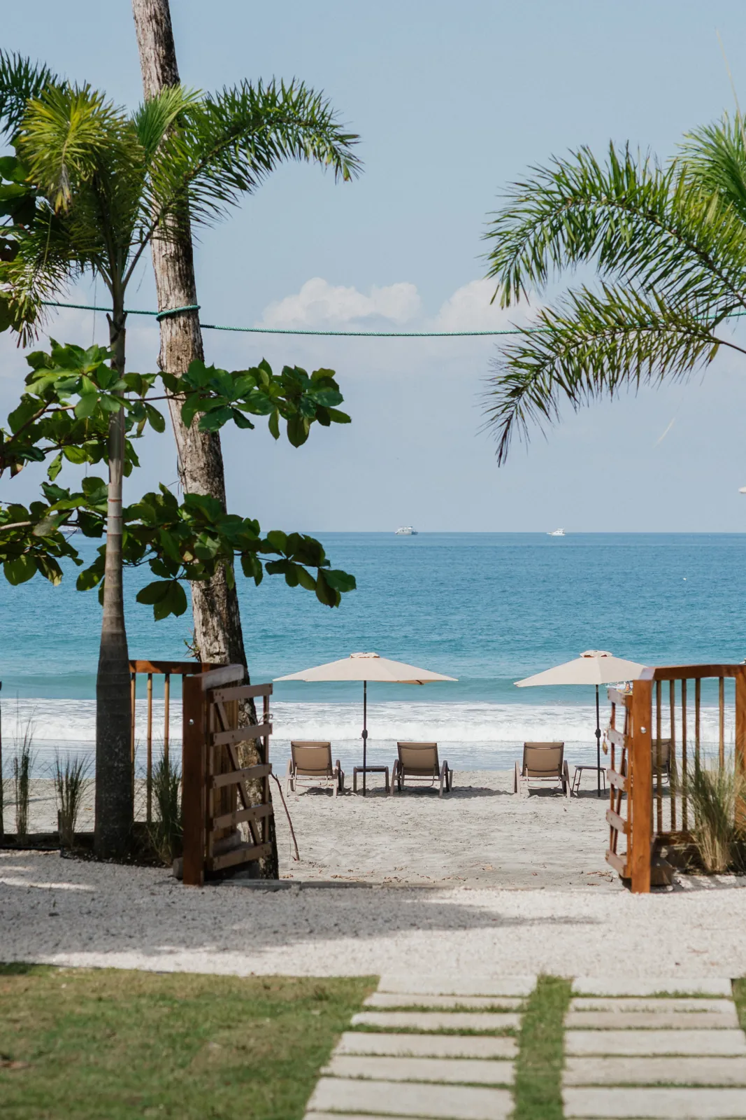 The wooden gate from Miamar's garden onto Playa Espadilla, loungers and umbrellas on the sand